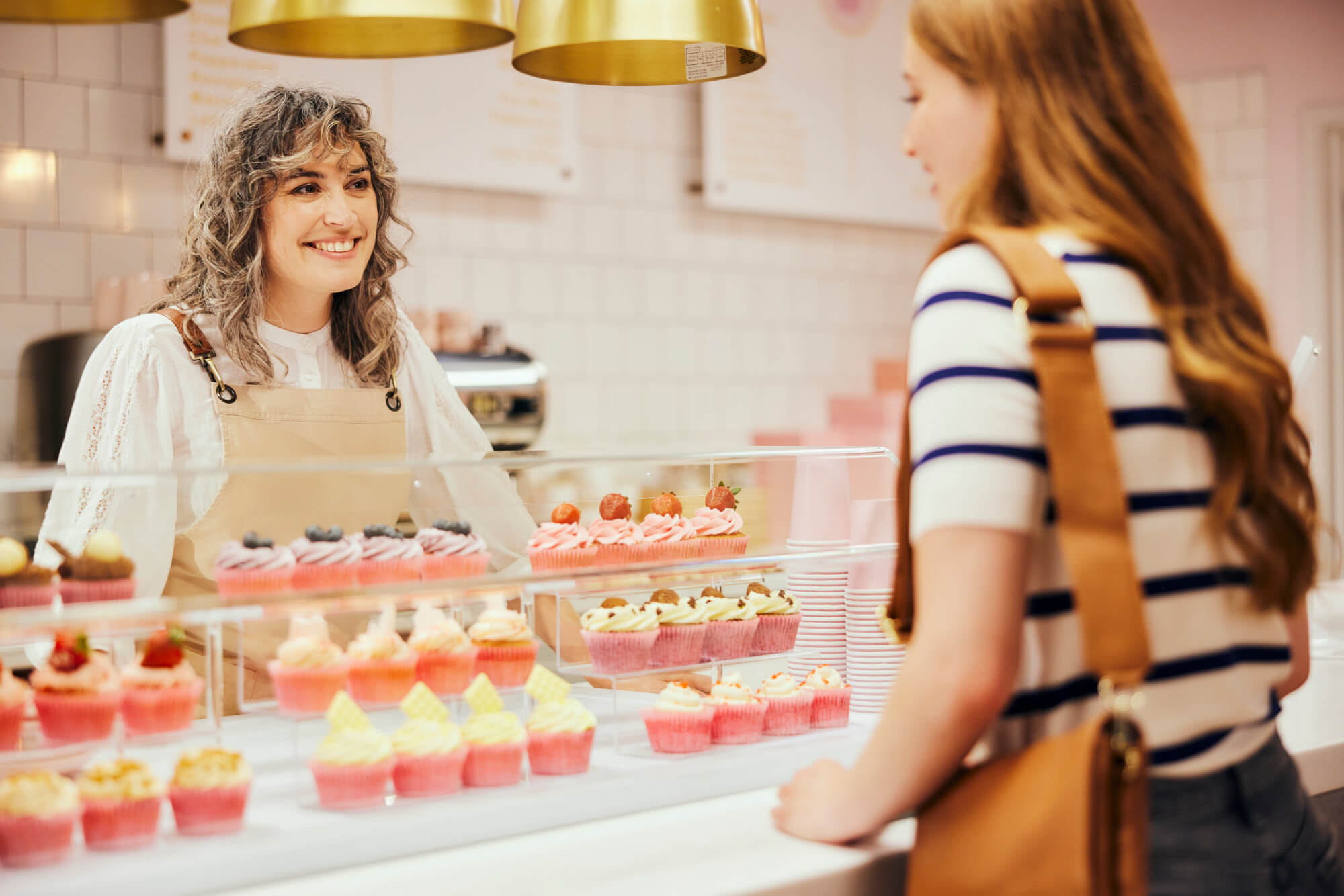 Woman small business owner talking to customer in cake shop