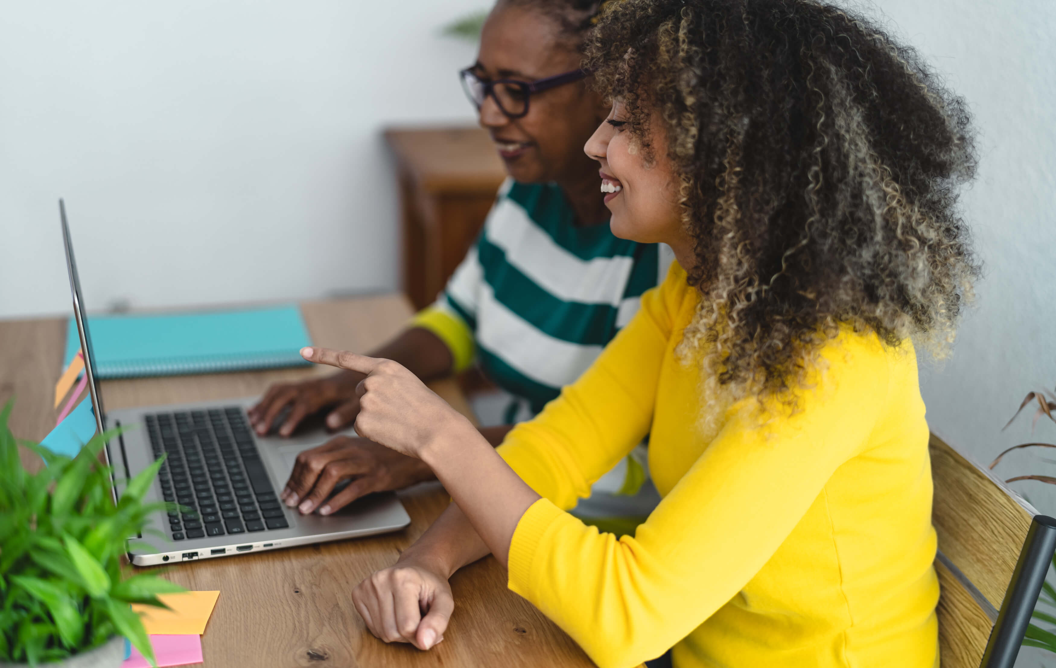 two women working on laptop smiling