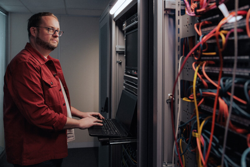 Man standing in front computer terminal in a datacentre